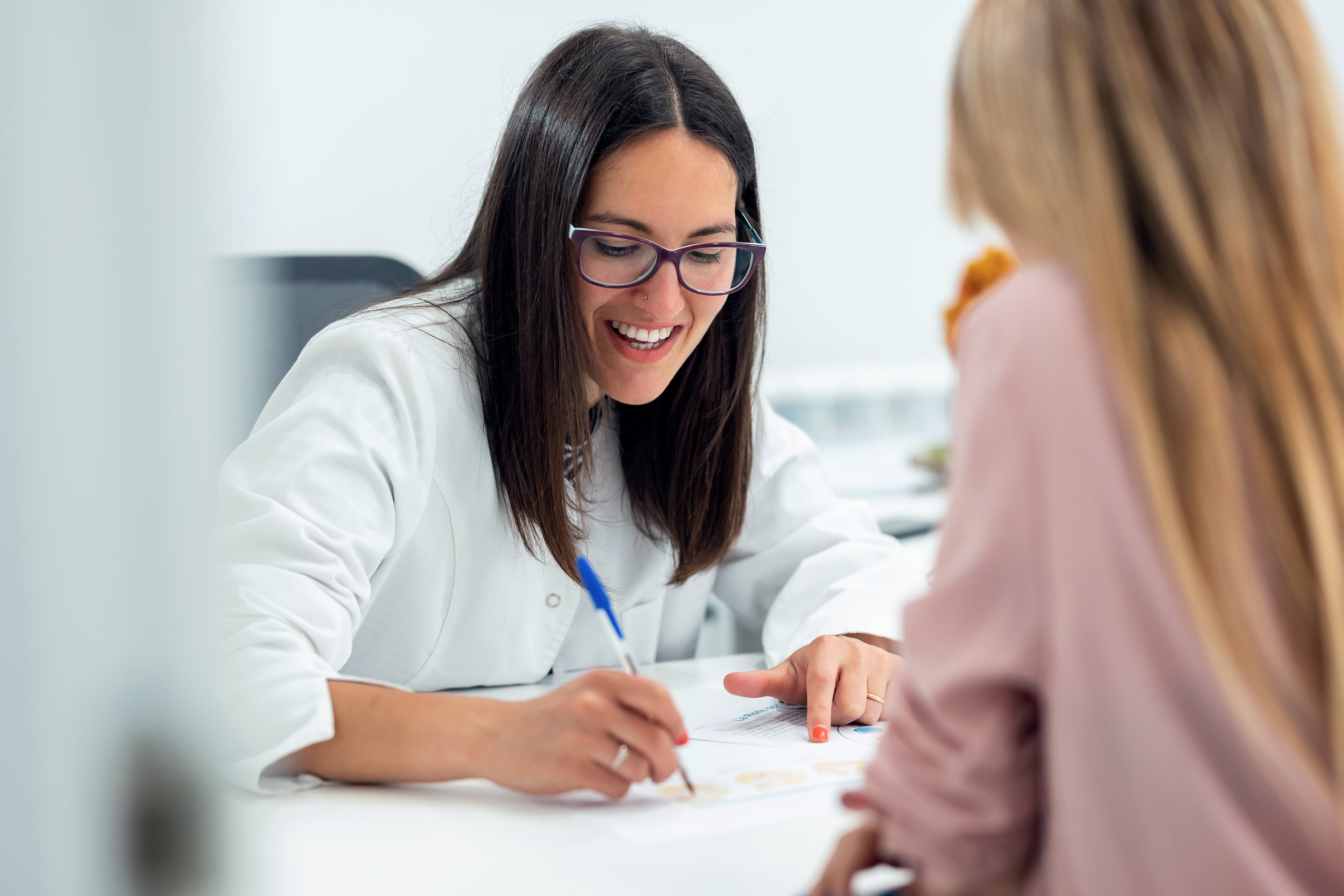 Medical professional explaining something to a person while writing notes on a document