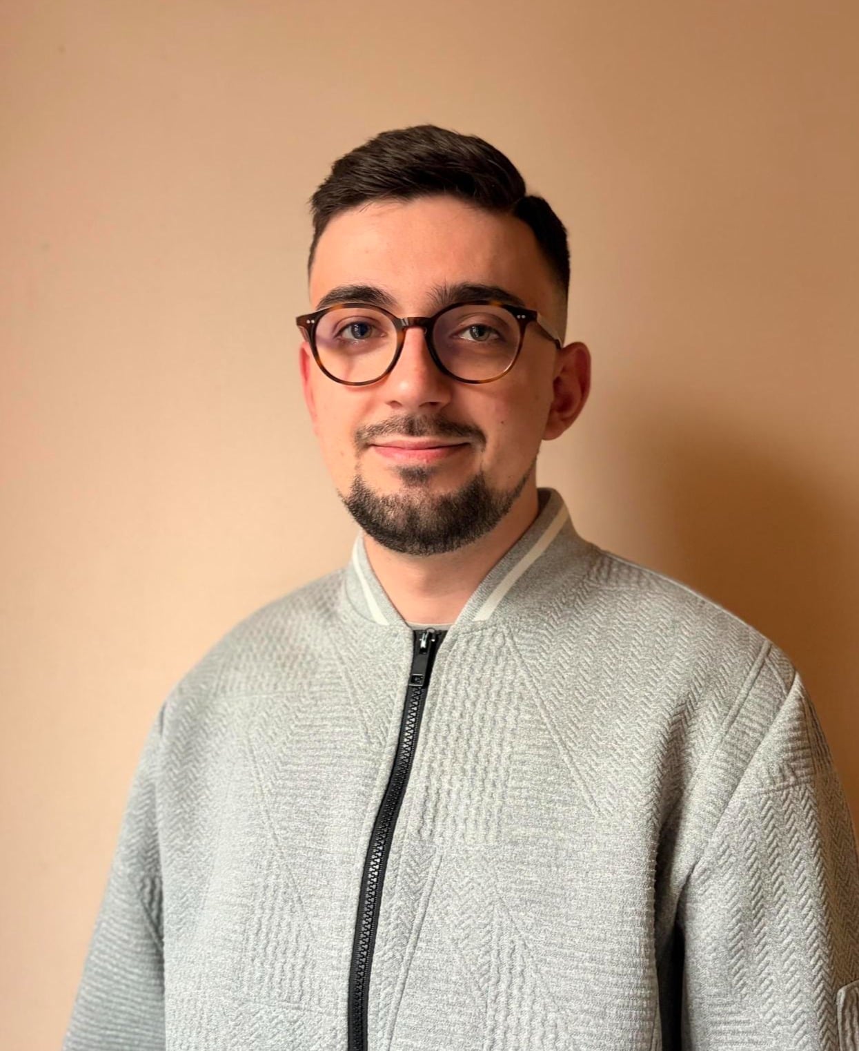 Porträt von Stiven Pajovi, Finance Specialist, mit Brille und hellgrauer Jacke.
