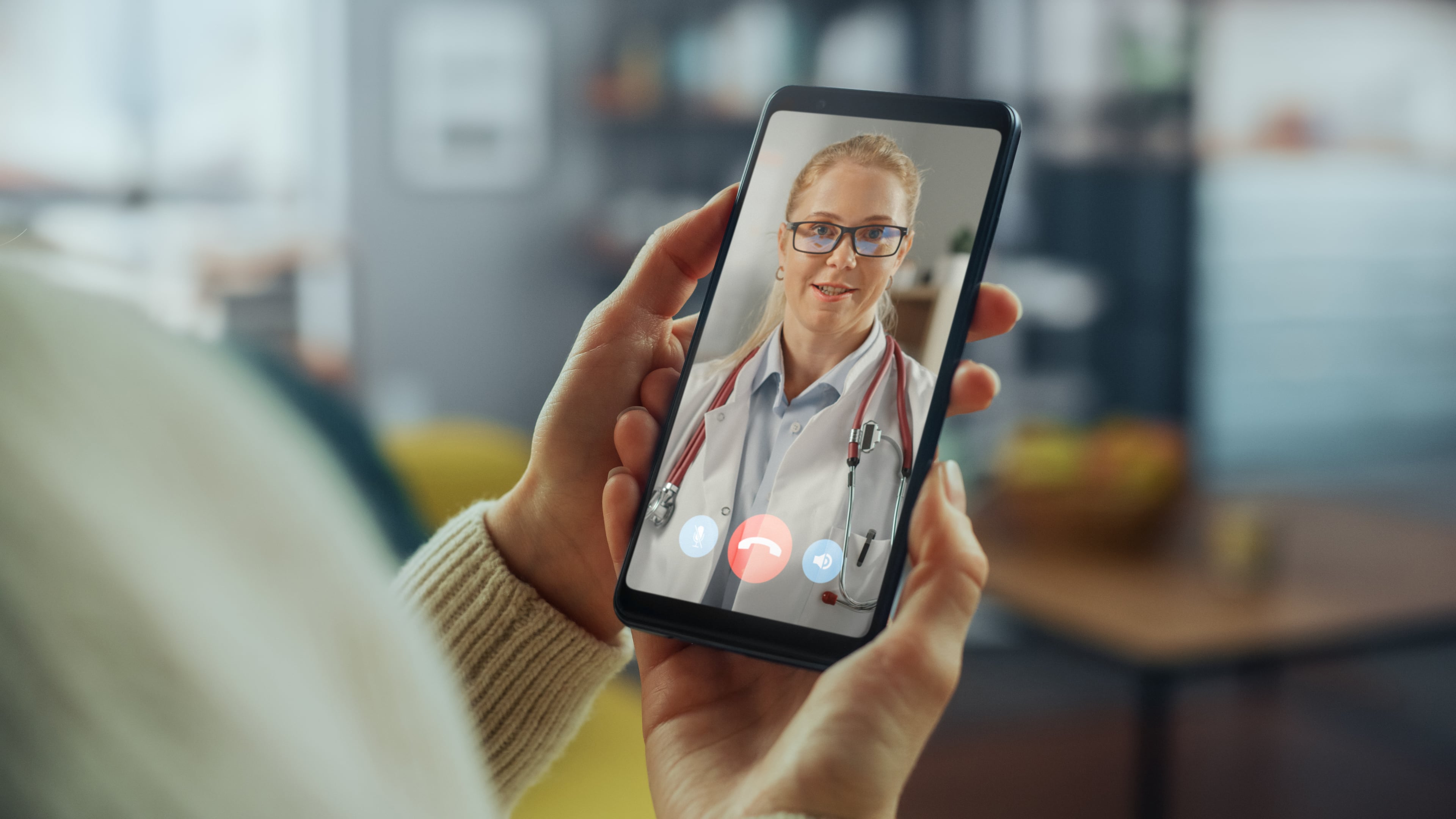 Person holding a smartphone during a video consultation with a doctor in a telemedicine session.