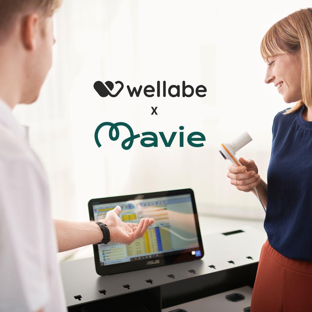 Mavie x wellabe Two people reviewing health data on a screen together. Above them are the logos of wellabe and Mavie, connected by an “x” indicating a partnership.