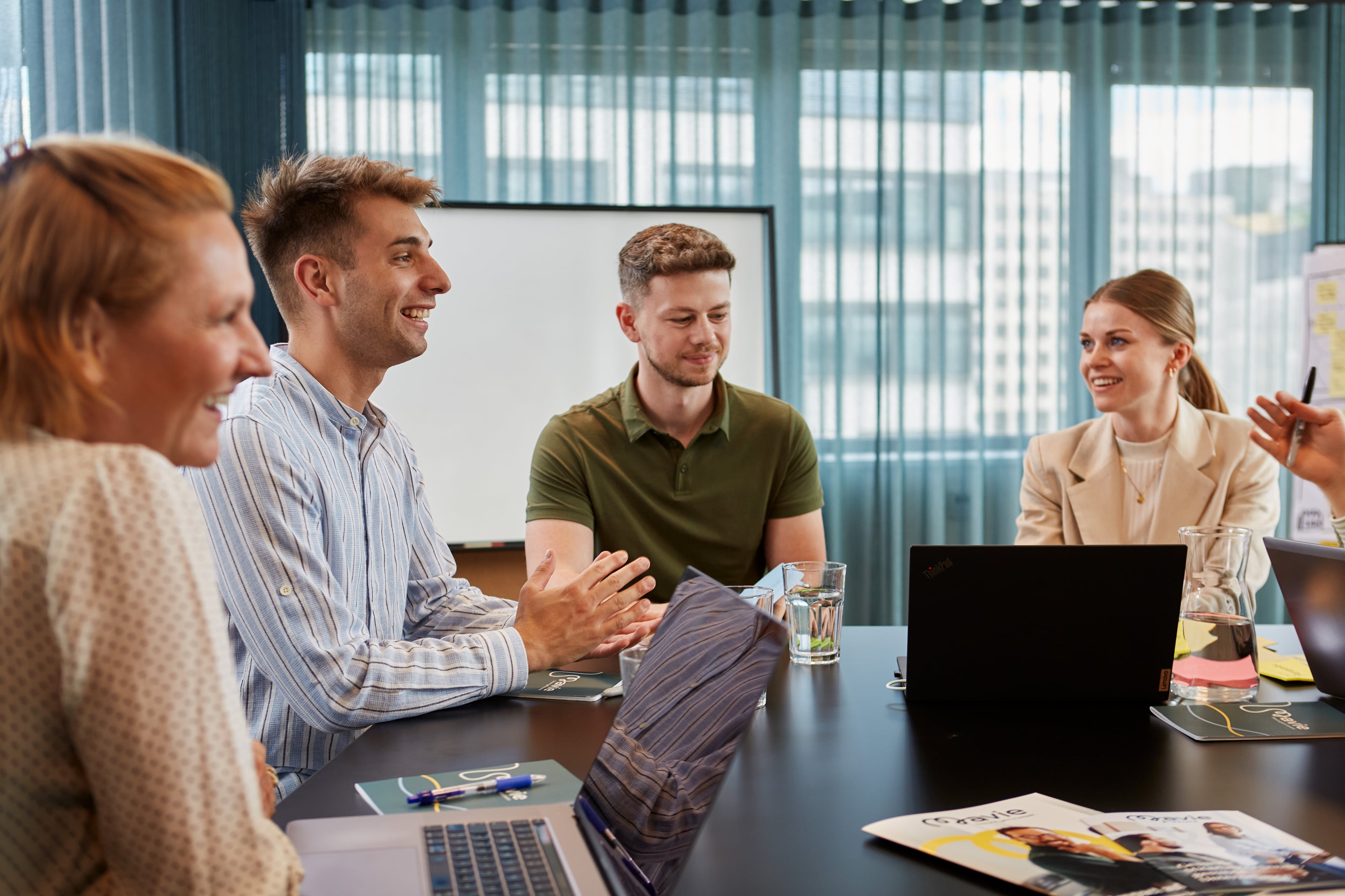 Team members meeting in a conference room and discussing ideas in a positive and collaborative work environment.