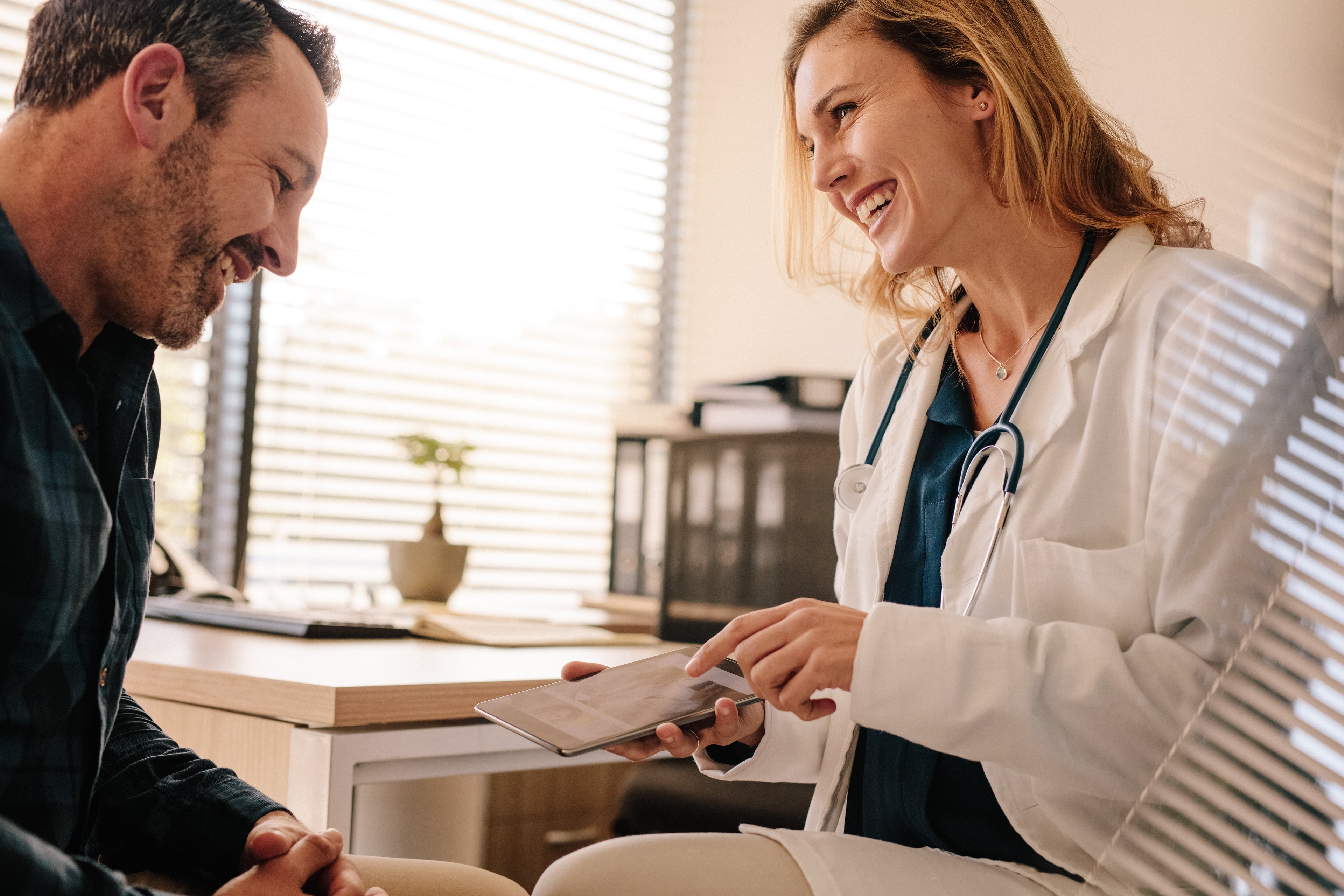 Doctor discussing medical information with a patient using a tablet in a clinic.