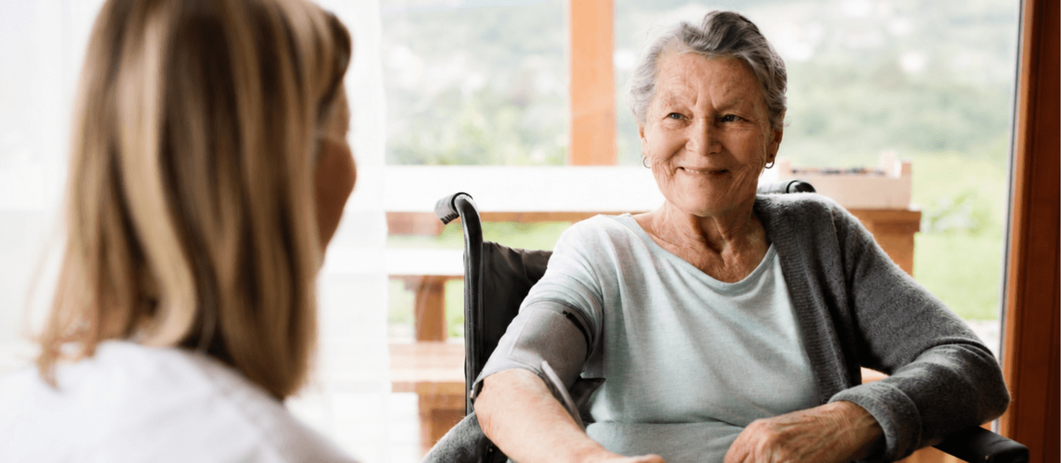 Healthcare professional measuring the blood pressure of an elderly woman during a home care visit.