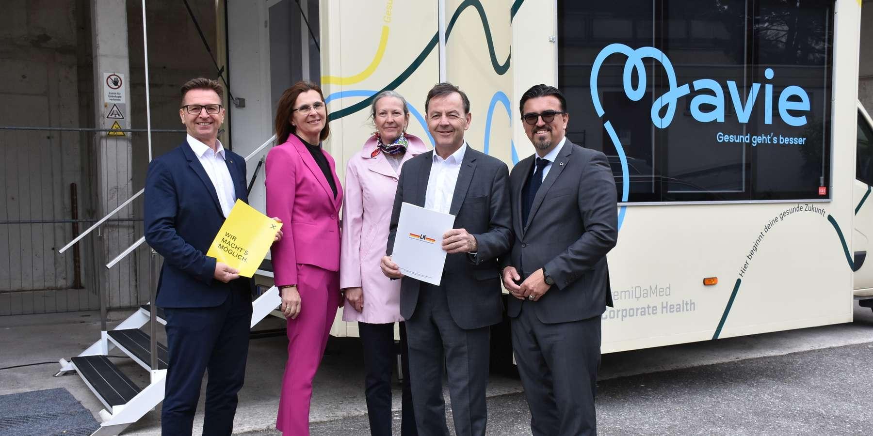 Iko Burgenland Five people standing in front of the Mavie Health Mobil, holding documents. The group appears formal and businesslike – possibly during a partnership event or presentation.