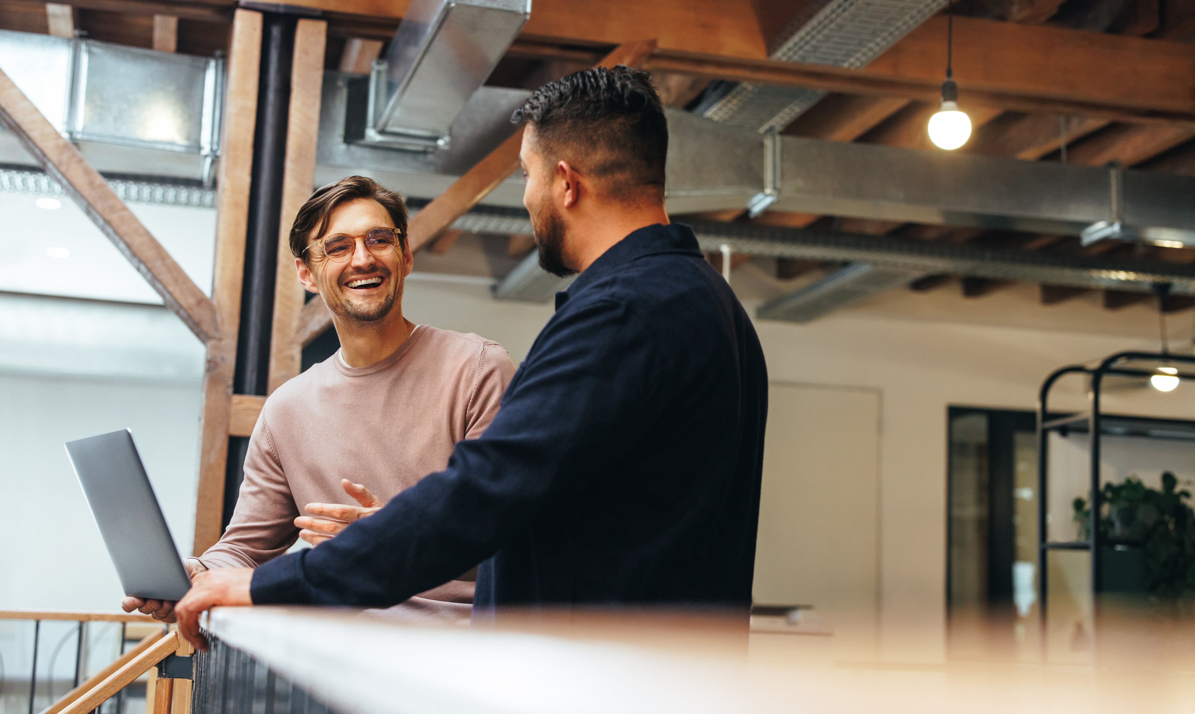 Two colleagues talking in a modern office and exchanging ideas in a relaxed atmosphere.