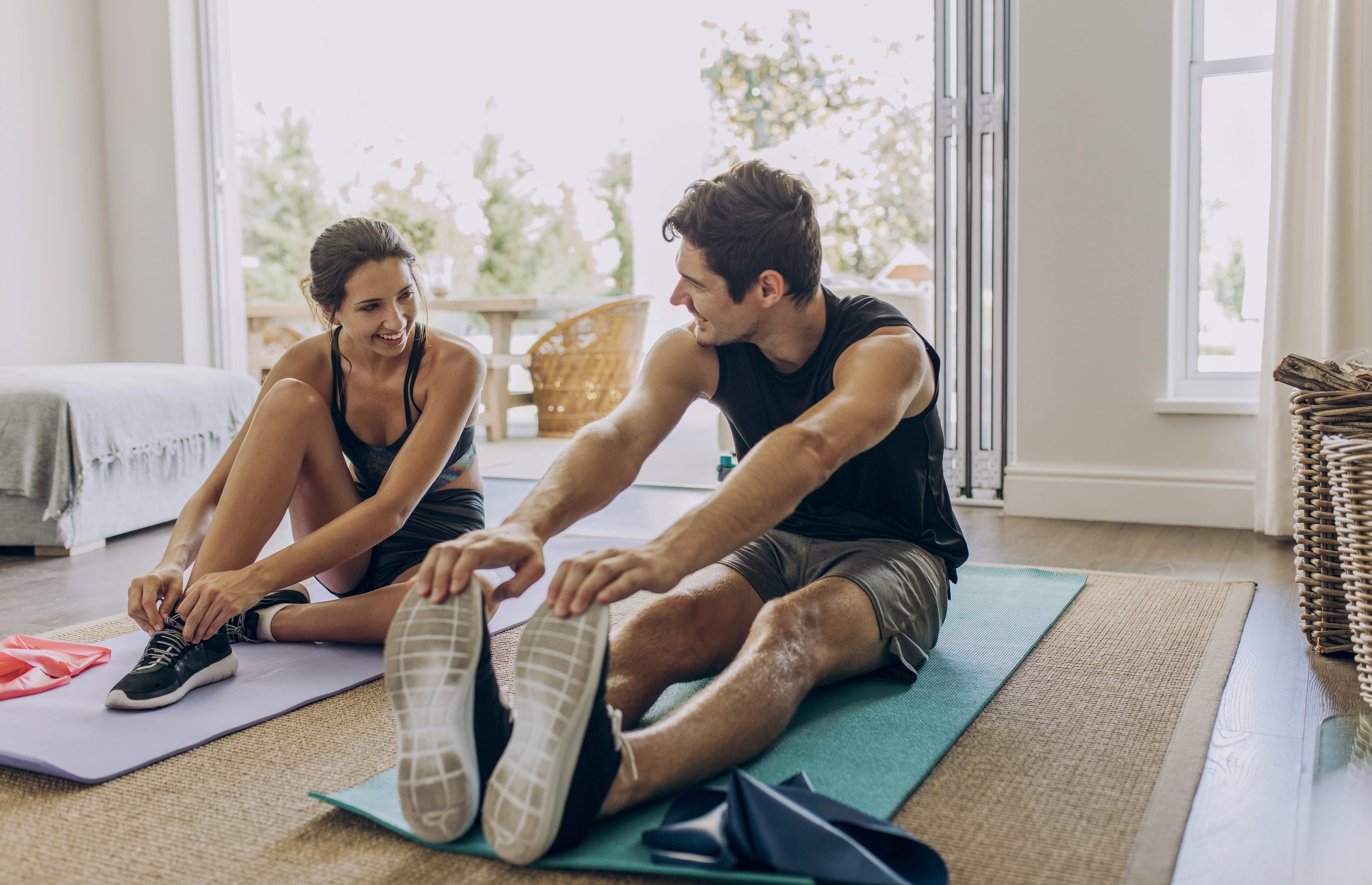 Mann und Frau beim Stretching auf der Matte in ihrer Wohnung