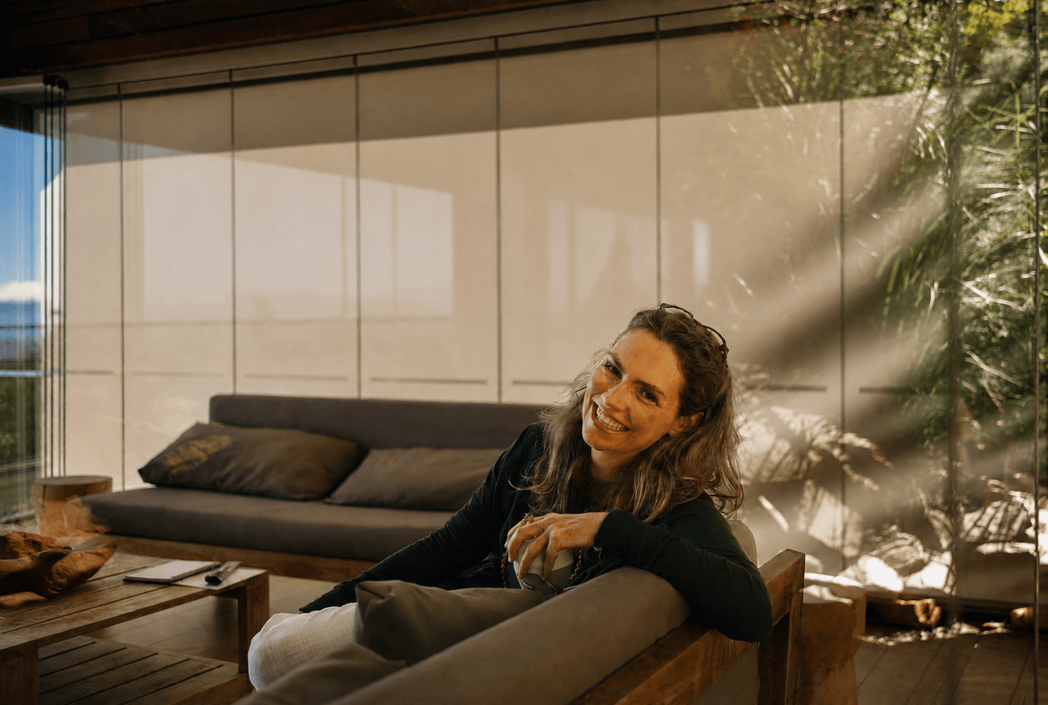 Smiling woman relaxing in a calm, sunlit room and enjoying a moment of rest and recovery.